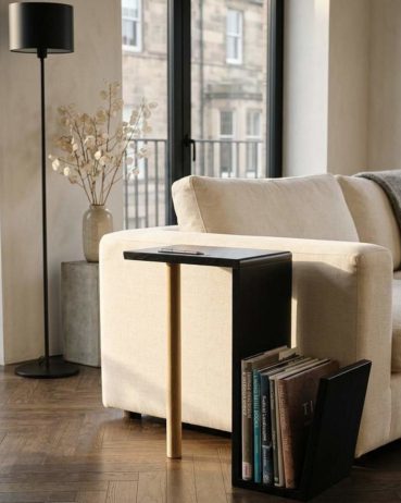 Designed and made in Edinburgh the contemporary black oak side table features a storage section for books and magazines. The table sits next to a couch.