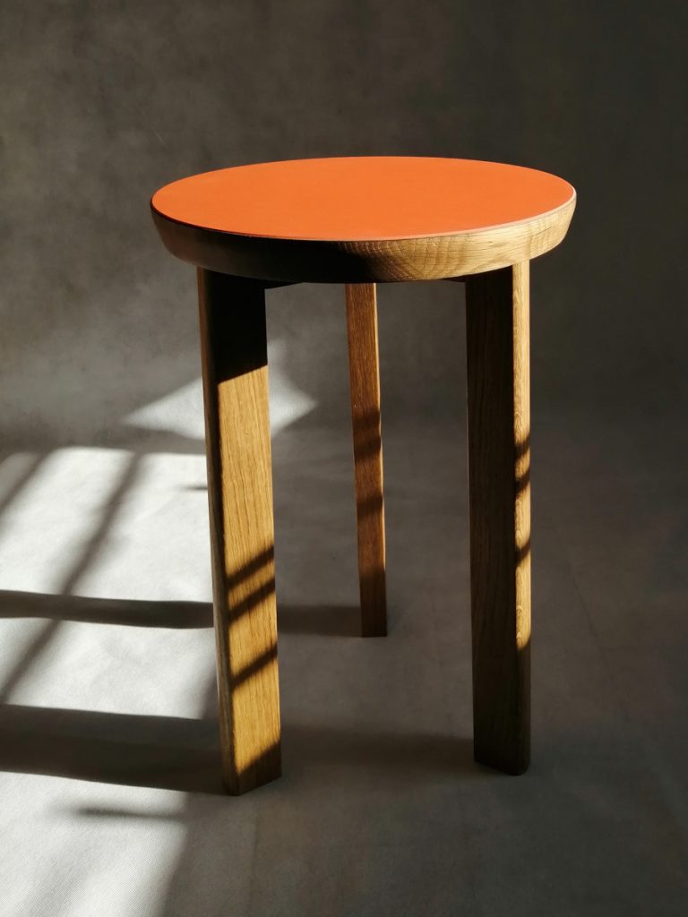 Three legged solid oak side table with orange linoleum top